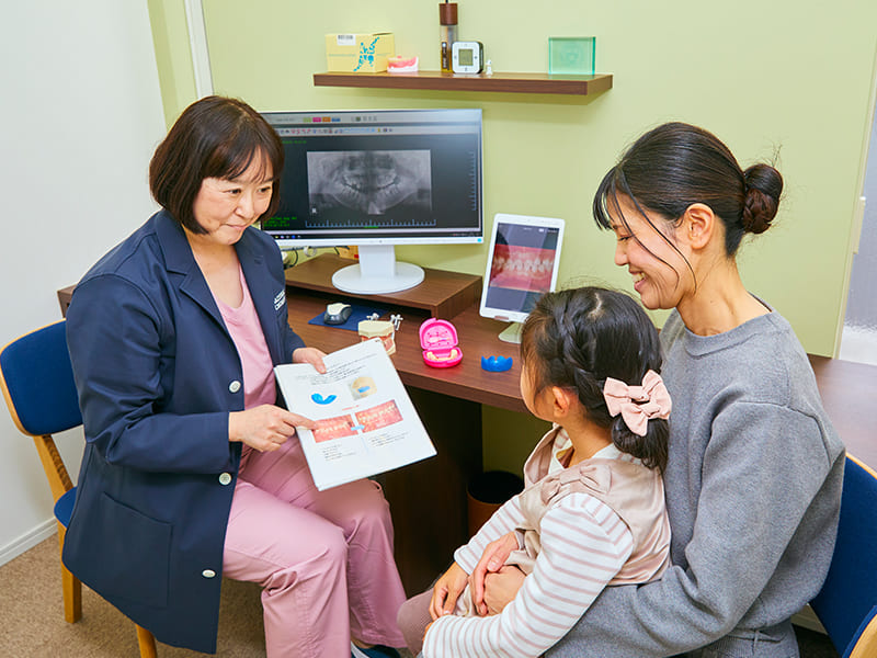 女性歯科医師より診断・治療方針の説明をうける親子